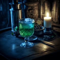 a green drink sitting on top of a table next to a candle