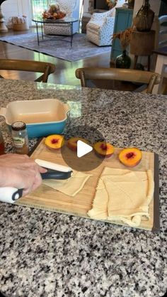 a person cutting up peaches on top of a wooden cutting board in a kitchen