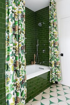 a green tiled bathroom with white and black tile flooring, shower curtain, and bathtub