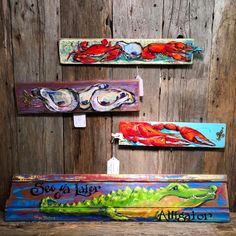 three wooden signs with lobsters and sea animals painted on them hanging on a wall