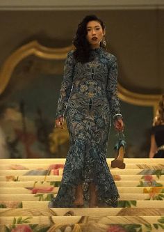 a woman is walking down the stairs in a dress with floral patterns and high heels