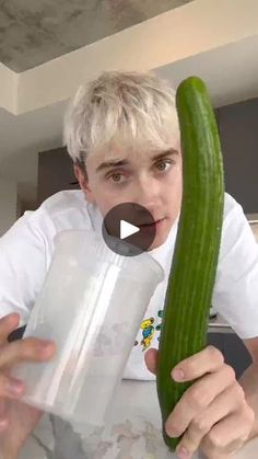 a man holding a large cucumber in front of his face