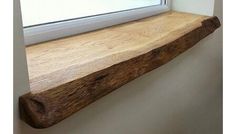 a wooden shelf sitting next to a window in a bathroom under a window sill