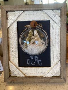 a christmas ornament hanging in a frame on a counter with the words merry christmas