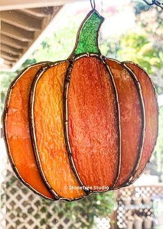 a stained glass pumpkin hanging from a window