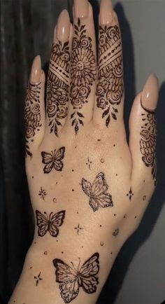 a woman's hand with henna tattoos and butterflies on the palm, which is decorated with intricate designs