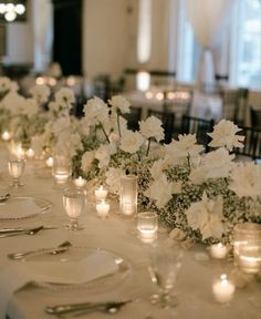 white flowers and candles are lined up on the table for a formal dinner or reception