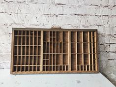 an old wooden box with bars on the bottom and sides is sitting against a white brick wall