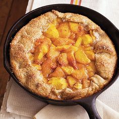 a skillet filled with fruit sitting on top of a white cloth next to a wooden table