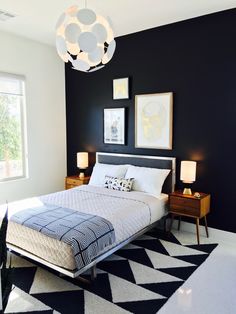 a black and white bedroom with a bed, nightstands, lamps and pictures on the wall