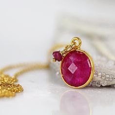 Back in stock! This striking Ruby necklace looks rich and exotic, and is perfect for adding colour to any outfit or occasion. Featuring a sparkling, round, cut and faceted ruby set in a bezel setting and paired with a dangling ruby gem. Available in various lengths. Rubies are the birthstone for July and the 40th wedding anniversary. Ruby jewelry makes a perfect romantic gift for a loved one, whether for a birthday, anniversary or Valentine's Day, as Rubies have always been associated with love Spiritual Gemstone Necklaces For Celebration, Gemstone Necklace With Round Pendant For Celebration, Unique Ruby Gemstone Necklace, Unique Ruby Necklace For Gift, Handmade Ruby Spiritual Jewelry, Handmade Spiritual Ruby Jewelry, Ruby Gemstone Necklace For Anniversary, Gold Ruby Gemstone Necklace, Unique Handmade Ruby Necklaces