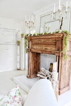 an old fireplace with candles and greenery on the mantle in a white living room