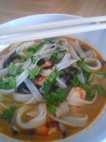 a bowl of soup with noodles, shrimp and cilantro