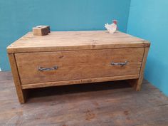 an old wooden dresser with two drawers on it's sides, against a blue wall