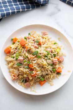 a white plate topped with rice and veggies on top of a marble counter