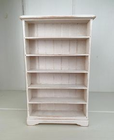 an old white bookcase is sitting on the floor