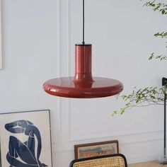 a red light hanging from a ceiling in a room with pictures on the wall and a chair