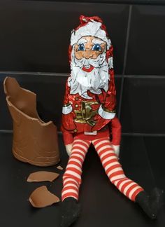 a santa clause doll sitting next to a broken chocolate egg