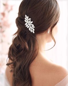 a woman wearing a wedding hair comb with flowers on it's back and side