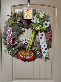 a wreath is hanging on the front door with candy bar ribbons and an ad for grin's free zone