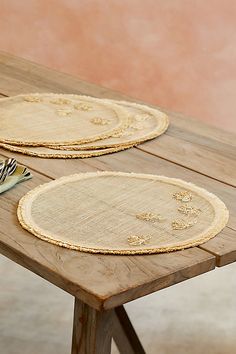 two round placemats sitting on top of a wooden table