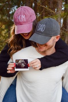 a man holding a woman who is wearing a baseball cap that says, mom and dad