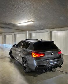 the rear end of a silver car parked in a parking garage with its lights on