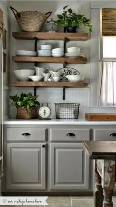 a kitchen with gray cabinets and shelves filled with dishes