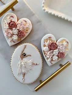 two heart shaped cookies decorated with flowers and a ballerina figure on a marble surface