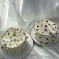 two cakes with white frosting and flowers on them