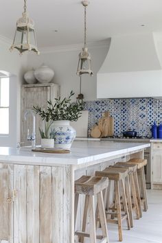 a kitchen island with stools in front of it and blue tiles on the back wall