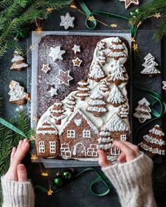 someone is decorating a gingerbread house with icing and christmas decorations on the table