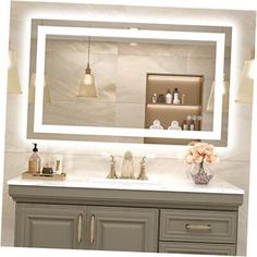 a bathroom vanity with a large lighted mirror above it and flowers on the counter top