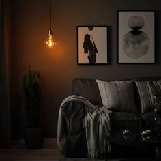 a living room with two pictures on the wall and a lamp hanging from the ceiling