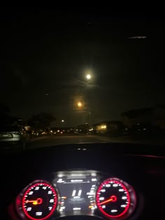 the dashboard of a car is lit up at night with full moon in the background