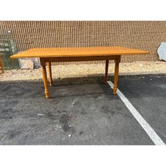 a wooden table sitting on top of a parking lot next to a brick wall in front of a building