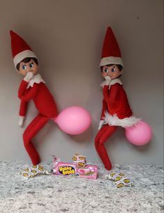 two elfs are playing with pink balls on the floor next to a candy bar