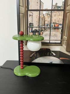 a green table with a lamp on it in front of a window overlooking a street