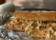 there is a sandwich that has been cut in half on tin foil with other food items