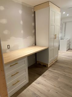 an empty room with white cabinets and wood flooring