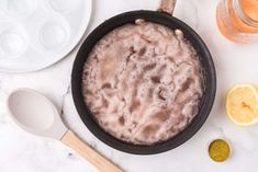 a pan filled with food sitting on top of a counter next to bowls and spoons