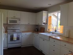 a kitchen with white cabinets and wooden counter tops