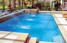 an outdoor swimming pool with waterfall and lounge chairs