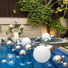 some balls are floating on the water in this backyard swimming pool with trees and bushes behind it