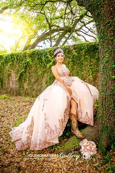 a woman in a dress sitting on the ground next to a tree