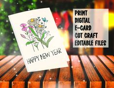 a happy new year card with flowers on it sitting on top of a wooden table