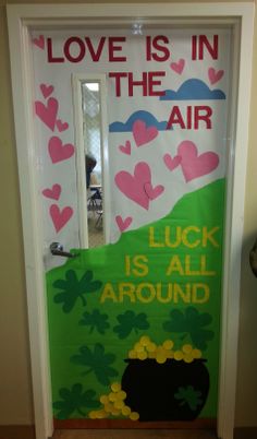 a door decorated with shamrocks and hearts that says love is in the air luck is all around