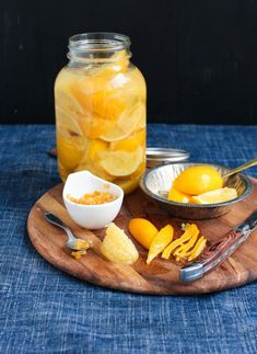 a wooden plate topped with sliced oranges next to a mason jar filled with liquid