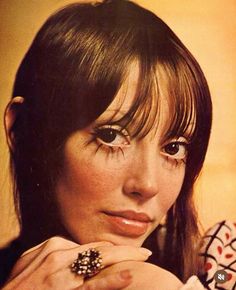 a close up of a person with a ring on her finger and wearing a shirt