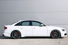 a white car is parked in front of a building with a large garage door behind it